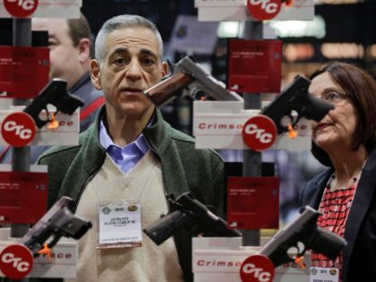 FILE - In this Jan. 14, 2014, file photo, knife manufacturers Les Halpern, left, and Marianne Halpern, of Three Rivers, Mass., examine a display of various handguns outfitted with laser sights on display at the Crimson Trace exhibit during the Shooting Hunting and Outdoor Trade Show in Las Vegas. The …