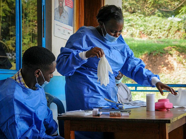 A health worker puts on her protective clothing before vaccinating people against Ebola at