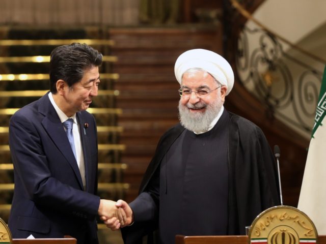 Iranian President Hassan Rouhani (R) shakes hands with Japanese Prime Minister Shinzo Abe,