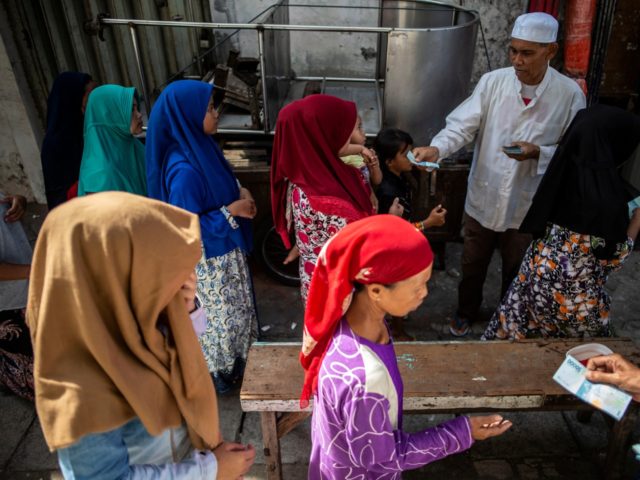 Indonesians queue up for charitable cash handouts in Surabaya on May 31, 2019, ahead of Ei