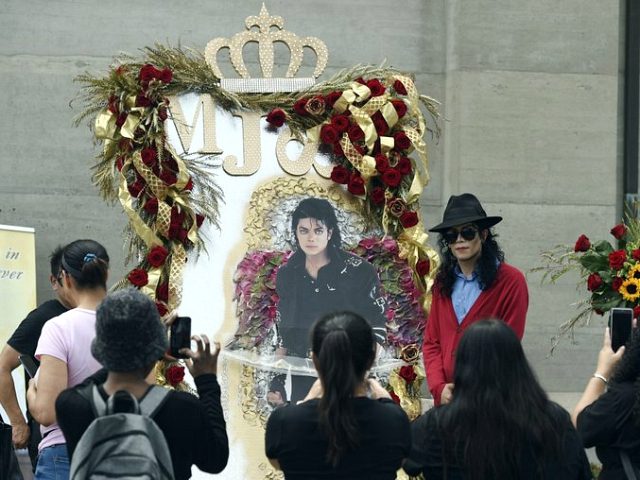 Michael Jackson impersonator Rem Garza of Long Beach, Calif., poses next to a shrine to th