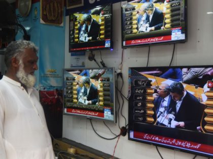 A Pakistani shopkeeper watches a television broadcast showing Pakistan's Minister of State