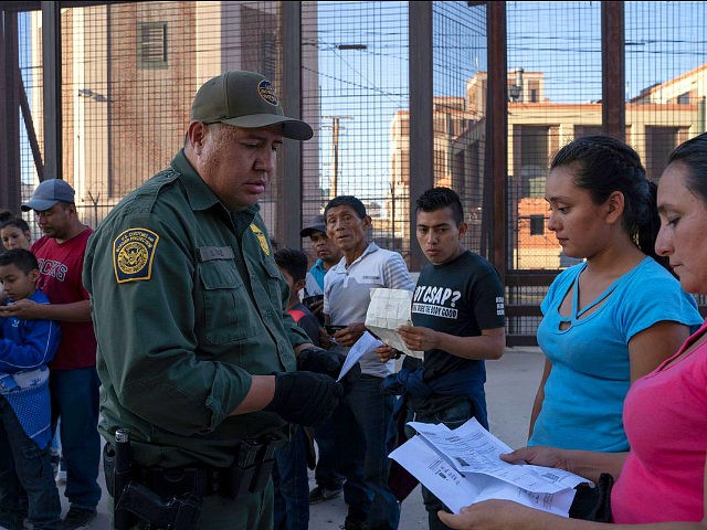 US Customs and Border Protection agent checks documents of a small group of migrants, who