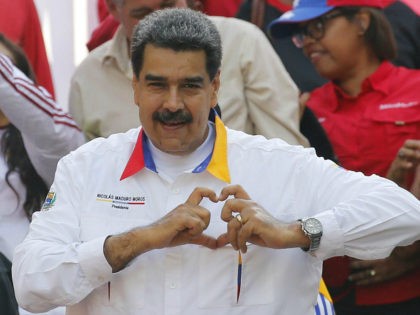 In this May 20, 2109 photo, Venezuela's President Nicolas Maduro flashes a hand-heart symbol to supporters outside Miraflores presidential palace in Caracas, Venezuela. Maduro said Thursday, May 23, 2019, that he iss inviting China's Huawei to help set up a 4G network in Venezuela, prompting opposition leader Juan Guaidó to …