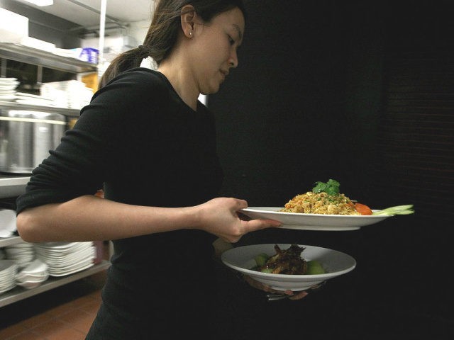 MAY 05: A waitress at Osha Thai Restaurant carries plates of food along with bowls of jasm