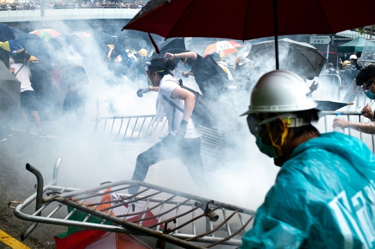 A protester throws a tear gas canister fired by police during a rally against a controversial extradition law proposal outside the government headquarters in Hong Kong on June 12, 2019. - Violent clashes broke out in Hong Kong on June 12 as police tried to stop protesters storming the city's parliament, while tens of thousands of people blocked key arteries in a show of strength against government plans to allow extraditions to China. (Photo by DALE DE LA REY / AFP) (Photo credit should read DALE DE LA REY/AFP/Getty Images)
