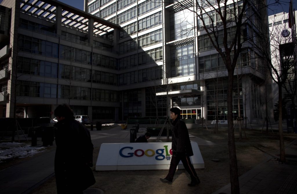 Security workers walk past a Google logo in front of Google China's headquarters building in Beijing, China, Monday, Jan. 25, 2010. The Chinese government denied involvement in Internet attacks and defended its online censorship Monday after the United States urged Beijing to investigate complaints of cyber intrusions in a dispute that has added tension to bilateral relations. (AP Photo/Alexander F. Yuan)