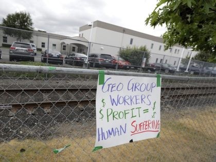 A sign opposing the Geo Group, the private contractor that operates the Northwest Detention Center, hangs on a fence outside the facility in Tacoma, Wash., Tuesday, July 10, 2018. The Trump administration rushed to meet a deadline Tuesday for reuniting dozens of youngsters forcibly separated from their families at the …