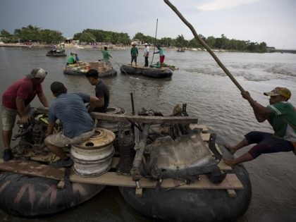 A raftsman hauls a load of used car parts across the Suchiate River toward Tecun Uman, Gua