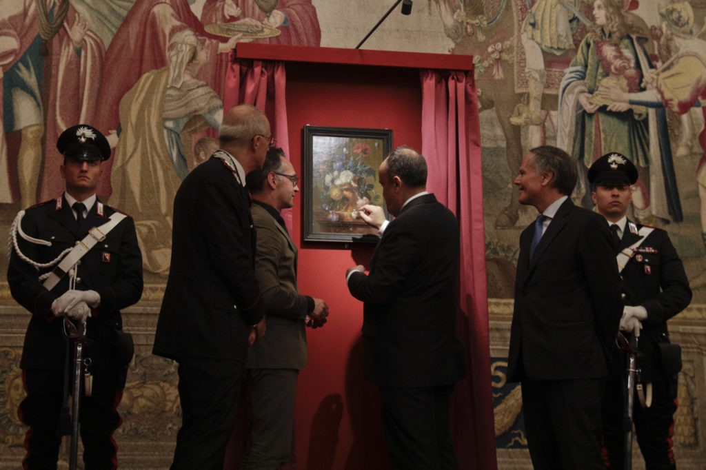 Italian Culture Minister Alberto Bonisoli, center, German Foreign Minister Heiko Mass, third from left, and Italian Foreign Minister Enzo Moavero Milanesi, second from right, attend the unveiling of the "Vase of Flowers" painting by Jan van Huysum, at the Pitti Palace, part of the Uffizi Galleries, in Florence, Italy, Friday, July 19, 2019. Germany returned the Dutch still-life after it was stolen by Nazi troops during WWII. (AP Photo/Gregorio Borgia)