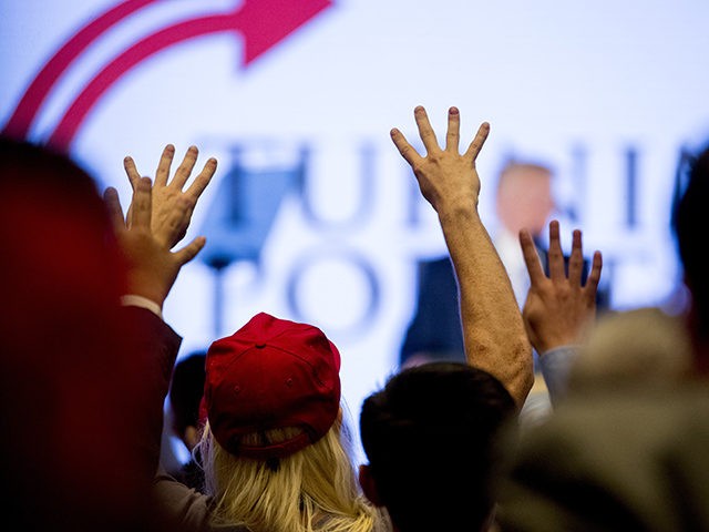 Members of the audience hold up four fingers and chant "Four More Years" as President Dona