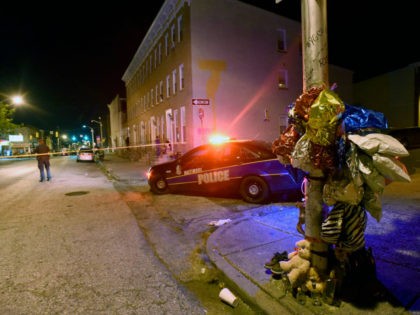A previously created memorial, right, stands as Baltimore police work at a scene where multiple people were shot in Baltimore, Saturday night, Sept. 24, 2016. Police said that none of the shootings were fatal. (AP Photo/Steve Ruark)