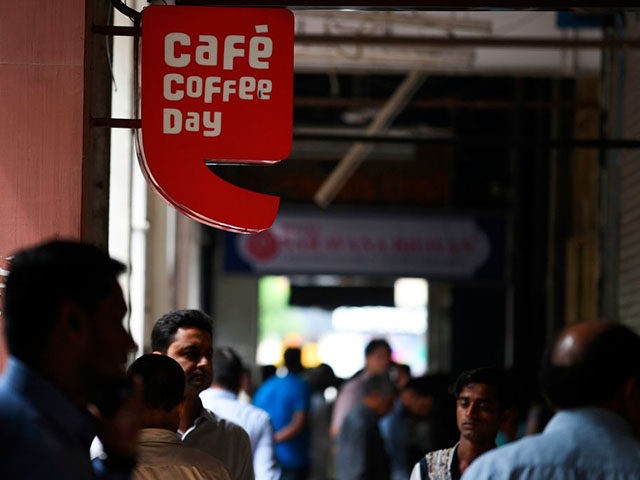 Pedestrians walk near the logo of Indian coffee retail chain 'Cafe Coffee Day' outside an outlet in New Delhi on July 30, 2019. - Indian police on July 30 launched a major hunt for one of the country's richest men, coffee tycoon V.G. Siddhartha, amid mounting fears for his safety. …