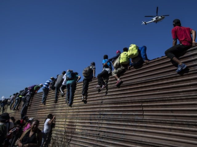 TOPSHOT - A group of Central American migrants -mostly Hondurans- climb a metal barrier on the Mexico-US border near El Chaparral border crossing, in Tijuana, Baja California State, Mexico, on November 25, 2018. - US officials closed the San Ysidro crossing point in southern California on Sunday after hundreds of …