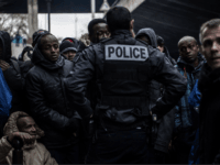 A policeman stand in front of Migrants waiting during the evacuation of a makeshift camp set up under Paris' ring road in the north of Paris' area of Porte de la Chapelle, on January 29, 2019, in an operation led by local authorities to shelter volunteer migrants in nearby gymnasiums …