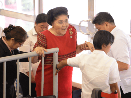 Philippine former first lady Imelda Marcos (in red) is helped by aides as she leaves after attending the proclamation of her daughter Senator Imee Marcos (not pictured), in Manila on May 22, 2019. - Allies of President Rodrigo Duterte stormed to a landslide victory in midterm polls, final results showed …