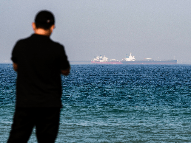 A man stands along a beach as tanker ships are seen in the waters of the Gulf of Oman off the coast of the eastern UAE emirate of Fujairah on June 15, 2019. (Photo by GIUSEPPE CACACE / AFP) (Photo credit should read GIUSEPPE CACACE/AFP/Getty Images)