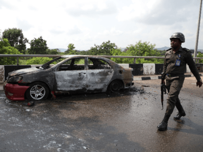 A policeman walks past a car burnt by supporters of an imprisoned leader of the Islamic Movement of Nigeria (IMN) Ibrahim Zakzaky around the national assembly building in Nigeria's capital Abuja, on July 9, 2019. - Supporters of an imprisoned Shiite cleric clashed on July 8, 2019 with security forces …