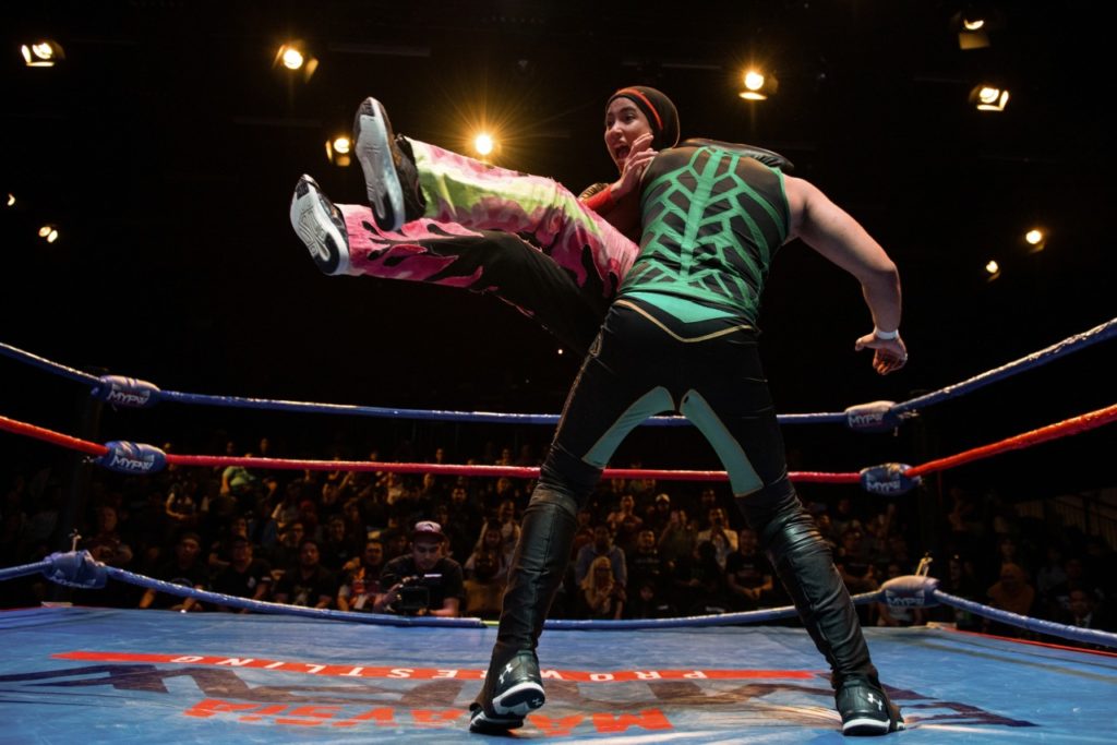 This picture taken on July 6, 2019 shows the hijab-wearing Malaysian wrestler known as Nor "Phoenix" Diana (L) wrestling with a male opponent during a match organised by Malaysia Pro Wrestling in Kuala Lumpur. - A hijab-wearing, diminutive Malaysian wrestler known as "Phoenix" cuts an unusual figure in the ring, a female Muslim fighter taking on hulking opponents in a male-dominated world. (Photo by Mohd RASFAN / AFP) / TO GO WITH Malaysia-wrestling-religion-Islam, FEATURE by Patrick LEE (Photo credit should read MOHD RASFAN/AFP/Getty Images)