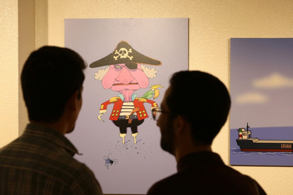 People view caricatures at the "Pirates of the Queen" cartoon exhibition showing artwork by Iranian artists portraying Britain's Queen Elizabeth II as a "pirate" over the seizure of an Iranian oil tanker earlier in the month, at the Osveh Art and Cultural Center in the capital Tehran on July 30, 2019. - Historically strained ties between Tehran and London worsened when British Royal Marines took part in the seizure of Iran's "Grace 1" oil tanker off UK overseas territory Gibraltar on July 4. That was followed by the seizure by Iran's Islamic Revolutionary Guard Corps of a UK-flagged tanker in the Strait of Hormuz on July 19 -- in what Britain called a "tit-for-tat" move. Forty cartoons have gone on display to throw the spotlight on the British seizure, which saw supreme leader Ayatollah Ali Khamenei accuse the "vicious British" of "piracy". (Photo by ATTA KENARE / AFP) (Photo credit should read ATTA KENARE/AFP/Getty Images)