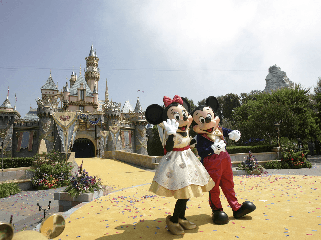 Disney characters Mickey Mouse and Minnie wave to a crowd of people in front the Sleeping