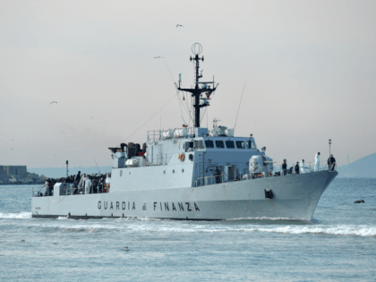 Rescued migrants stand aboard the Italian Guardia di Finanza vessel Denaro upon arrival to