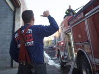 BALTIMORE, MD - APRIL 28: A firefighter motions to a fireman spraying water from a firetruck to extinguish the smoldering remains of a senior center set ablaze during night riots on April 28, 2015 in Baltimore, Maryland. A state of emergency has been declared in Baltimore following violent protests which …