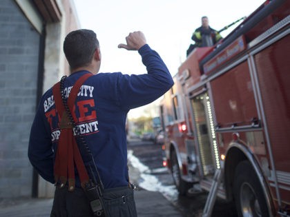 BALTIMORE, MD - APRIL 28: A firefighter motions to a fireman spraying water from a firetru