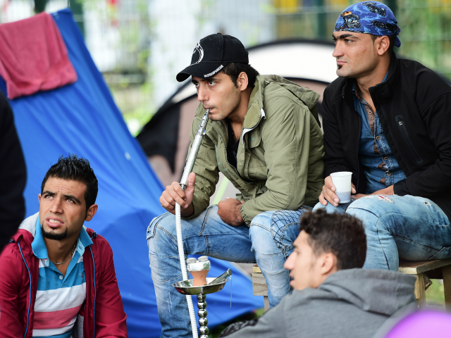 Men smoke from a waterpipe at a makeshift tent camp in a park in Brussels on September 9, 2015, as they wait to have their asylum claims processed. The camp is situated across the "Office des Etrangers" (Foreigner's Office), where the number of refugees encamped has passed the 250 inscriptions …