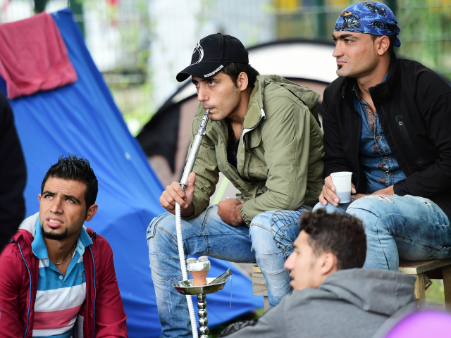 Men smoke from a waterpipe at a makeshift tent camp in a park in Brussels on September 9,