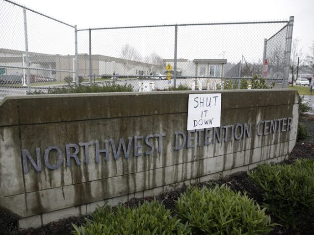 A sign that reads "shut it down" is pictured at the Northwest Detention Center as people a