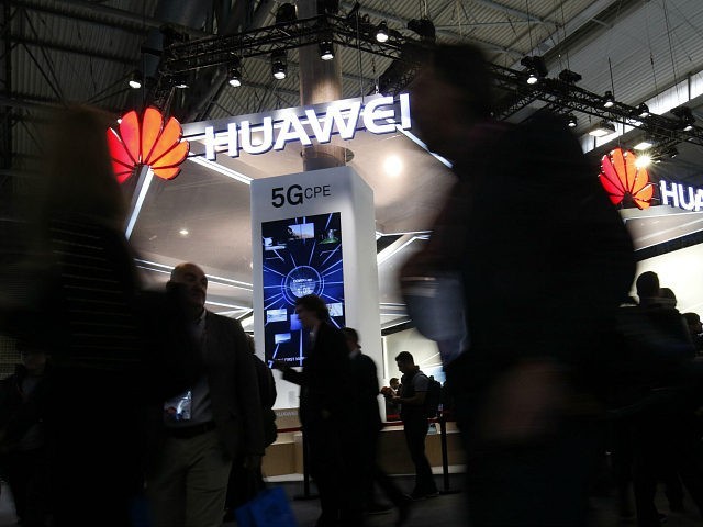 People walk by the Huawei stand at the Mobile World Congress (MWC), the world's biggest mo