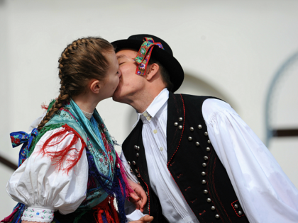 A young couple, dressed in traditional garb and members of local folklore dance group, kis