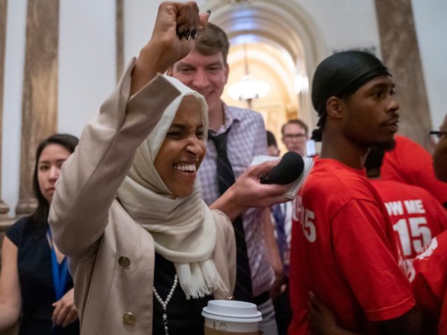 Rep. Ilhan Omar, D-Minn., a target of racist rhetoric from President Donald Trump, responds to cheers from visitors at the Capitol seeking a raise in the minimum wage, as she leaves the chamber following votes, in Washington, Thursday, July 18, 2019. (AP Photo/J. Scott Applewhite)