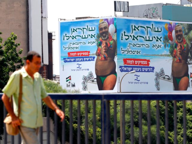 A picture taken on July 23, 2019 in the Israeli coastal city of Tel Aviv, shows a giant billboard bearing the portrait of Hamas leader Ismail Haniyeh super-imposed on a body of a man in a swimsuit and carrying a suitcase of money. - Hebrew writing on the billboard reads: …