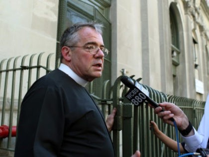 Father John Duffell, parish pastor, talks to reporters outside the Ascension School in New