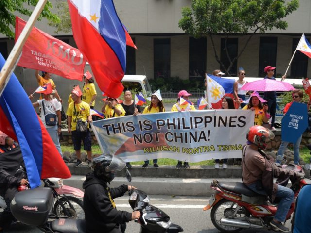 Protesters hold placards as motorists speed past during a rally in front of the Chinese consulate in Manila on July 13, 2019, to coincide with anniversarry of arbitral ruling by United nations on the South China sea. - Protesters decended on the Chinese consulate in Manila, to oppose the Asian …