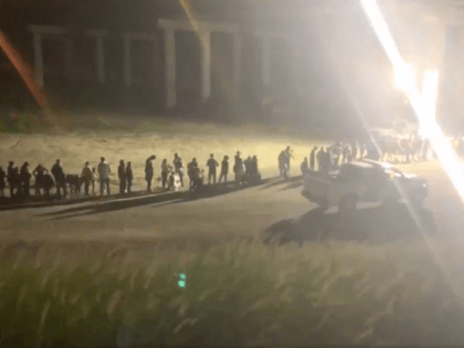 Migrants line up near the Rio Grande by Rincon Village, Texas, after illegally crossing th