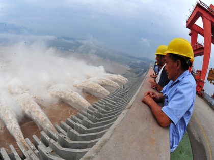 This picture taken on July 24, 2012 shows workers watching as water is released from the Three Gorges Dam, a gigantic hydropower project on the Yangtze river, in Yichang, central China's Hubei province, after heavy downpours in the upper reaches of the dam caused the highest flood peak of the …