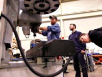 In a photo from Wednesday, Feb. 11, 2015 in Lansing, Mich., Lansing Community College, Brad Bancroft, left, operates a mill as Nate Joseph, center, and Adam Woodhams, right, look on in the advanced precision machining class. (AP Photo/Carlos Osorio)
