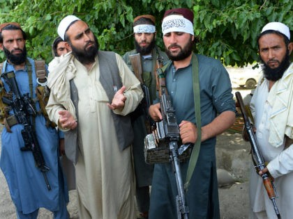 Afghan Taliban militants stand with residents as they took to the street to celebrate ceas