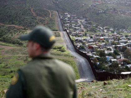 FILE - In this Feb. 5, 2019, file photo, Border Patrol agent Vincent Pirro looks on near a border wall that separates the cities of Tijuana, Mexico, and San Diego, in San Diego. Hundreds of thousands of people have been arriving at the border in recent months, many of them …