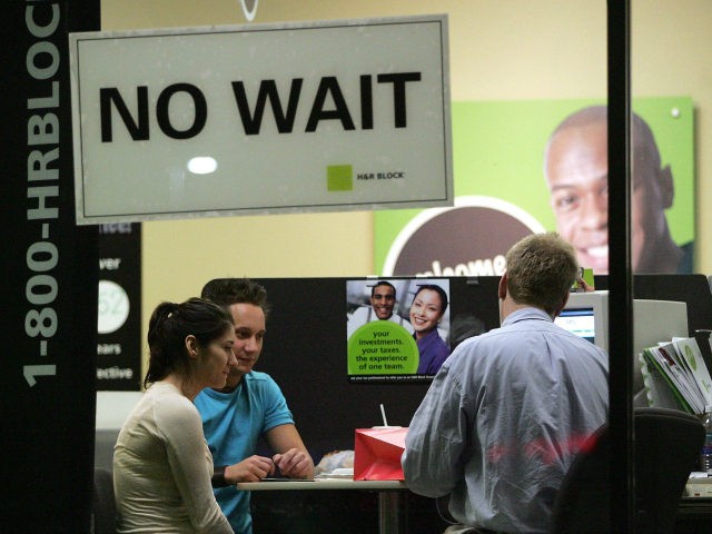 Visible through a window, an H&R Block tax preparer (R) assists Senada Imsirovic (L) sitting next to her friend Kevin Schwaner, with her taxes in an H&R Block office late-night April 13, 2006 in Des Plaines, Illinois. Some tax payers are waiting for the last minute before filing their income …