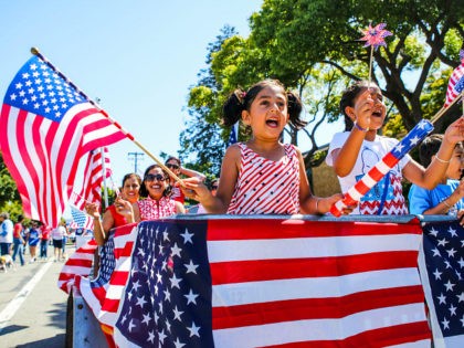 People wave American flags as they ride through 4th of July Parade in Alameda, California on Monday, July 4, 2016. / AFP / GABRIELLE LURIE (Photo credit should read GABRIELLE LURIE/AFP/Getty Images)
