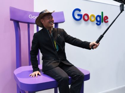 A visitor takes a selfie picture in front of the google stand of the Google stand showing