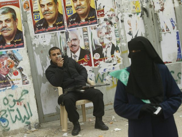 GAZA CITY, -: A Palestinian policeman plays with his mobile phone as a militant from the I