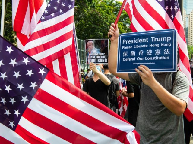 Protesters standing amid US flags hold up placards that read "President Trump, please liberate Hong Kong" as they gather at Victoria Park to participate in an anti-government march in Hong Kong on July 21, 2019. - Hong Kong is bracing for another huge anti-government march on July 21 afternoon with …