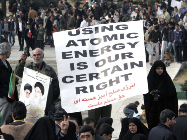 An Iranian protester holds a banner to defend their country's nuclear activities as they a