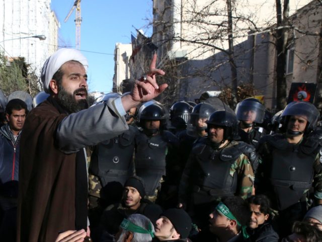 urrounded by policemen, a Muslim cleric addresses a crowd during a demonstration to denounce the execution of Saudi Shiite Sheikh Nimr al-Nimr, seen in poster, in front of the Saudi embassy in Tehran, Iran, Sunday, Jan. 3, 2016. Saudi Arabia announced the execution of al-Nimr on Saturday along with 46 …