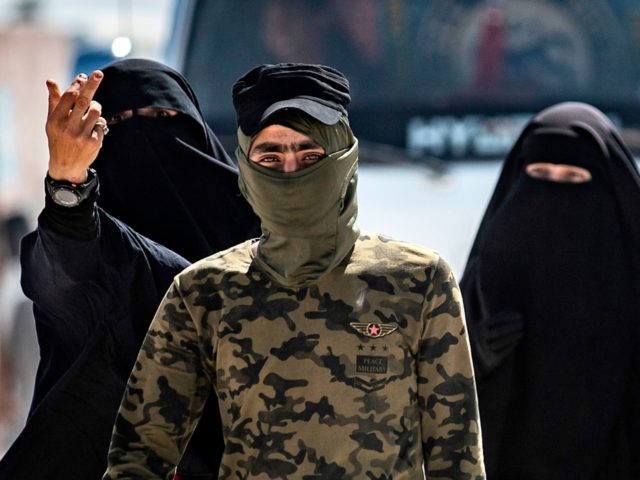 An internal security patrol member escorts women, reportedly wives of Islamic State (IS) g